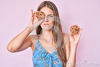 Young blonde girl holding cookie skeptic and nervous, frowning upset because of problem Stock Photo