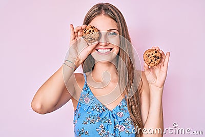 Young blonde girl holding cookie smiling with a happy and cool smile on face Stock Photo