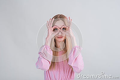 Young blonde girl makes funny grimaces in the studio on a white background. Stock Photo