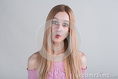 Young blonde girl makes funny grimaces in the studio on a white background. Stock Photo