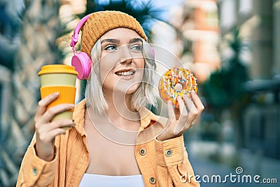 Young blonde girl using headphones having breakfast at the city Stock Photo