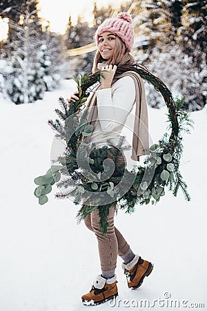 Blonde young lady with christmas wreath in winter forest Stock Photo