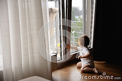 Young blonde mother having quality time with her baby boy son at family home flat - Wearing black budoir dress costume Stock Photo