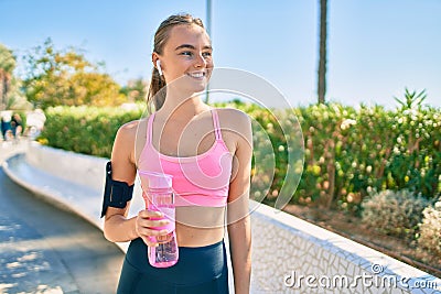 Young blonde sportswoman doing exercise drinking bottle of water at the city Stock Photo