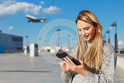 Young blonde woman booking fligt ticket by tablet outdoors Stock Photo