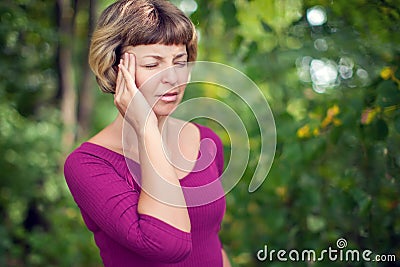 Young blonde woman having serious migrene suffering from horrible head ache feeling big pain outdoor. Healthcare, medicine and pe Stock Photo