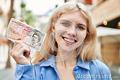 Young blonde woman holding english banknotes pounds, showing money smiling happy and confident outdoors Editorial Stock Photo