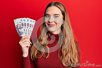 Young blonde woman holding russian 500 ruble banknotes looking positive and happy standing and smiling with a confident smile Stock Photo