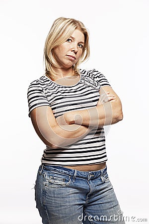 Young blonde woman in jeans crossed her arms over her chest. White background. Vertical Stock Photo