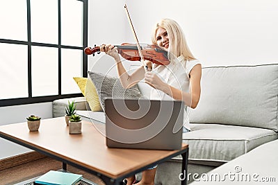 Young blonde woman musician smiling confident having online violin lesson at home Stock Photo