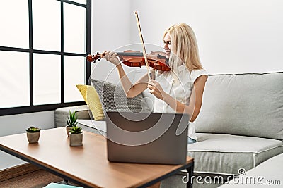 Young blonde woman musician smiling confident having online violin lesson at home Stock Photo