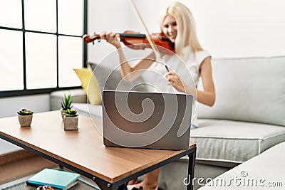 Young blonde woman musician smiling confident having online violin lesson at home Stock Photo