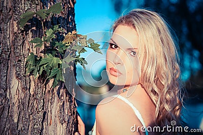 Young Blonde Woman next to a tree Stock Photo