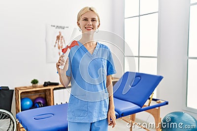 Young blonde woman physiotherapist smiling confident holding diploma at rehab clinic Stock Photo