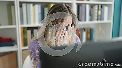 Young blonde woman student stressed covering face with hands at library university Stock Photo