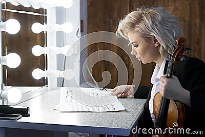 Young blonde woman violinist reads notes before a performance Stock Photo