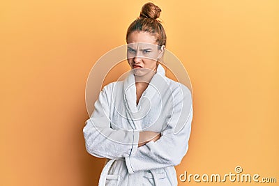 Young blonde woman wearing bathrobe skeptic and nervous, disapproving expression on face with crossed arms Stock Photo