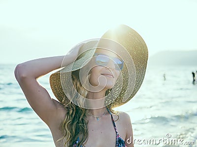 Young blondy girl in sunglasses and straw hat at the beach Stock Photo