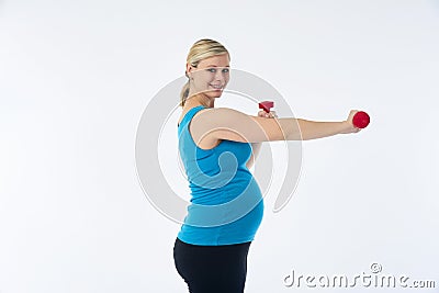 Young blondy pregnant woman in blue tank top does exercises with small red fitness dumbbells, white background. Stock Photo