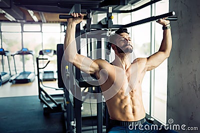 Young bodybuilder training in gym on machine Stock Photo