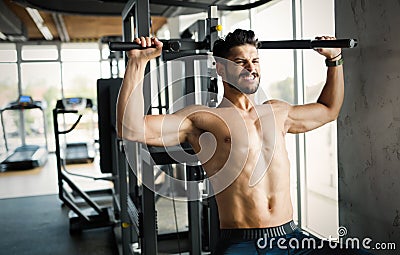 Young bodybuilder training in gym on machine Stock Photo