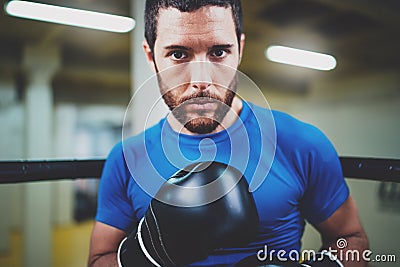 Young boxing man looking aggressive with boxing gloves on ring.Caucasian athlete in black gloves looking at the camera Stock Photo