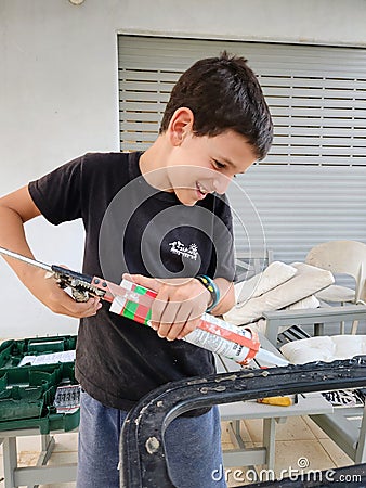 Young boy applying silicon on a metal frame Stock Photo