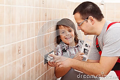 Young boy assisting his father installing electrical wall fixtures Stock Photo