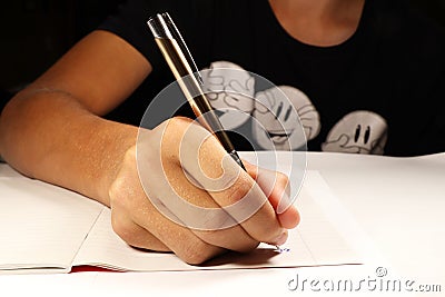 A young boy with black t-shirt writing dictation in english lesson. Elementary school. Stock Photo