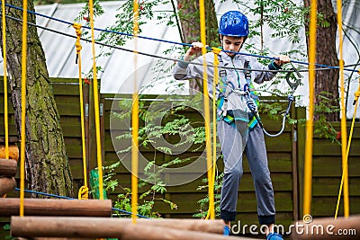 Young boy climbing pass obstacles in rope. Child in forest adventure park Stock Photo