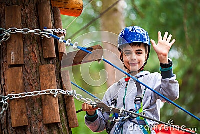 Young boy climbing pass obstacles in rope. Child in forest adventure park Stock Photo