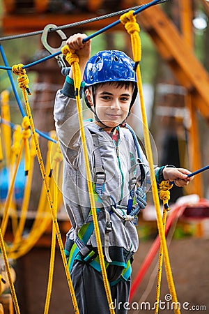Young boy climbing pass obstacles in rope. Child in forest adventure park Stock Photo