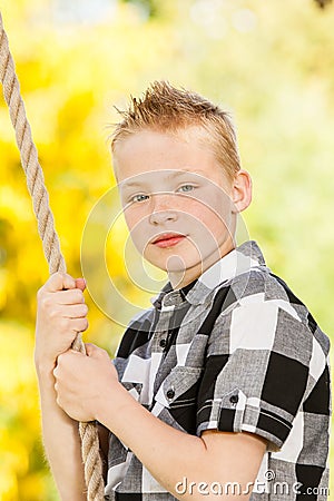 Young boy clutching a rope outdoors in the garden Stock Photo