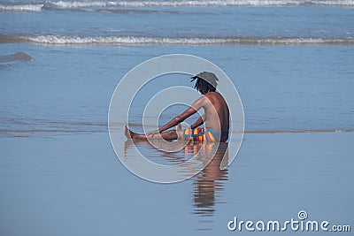 Young boy in colourful striped shorts plays in the waves at Port St Johns, Transkei, South Africa. Editorial Stock Photo