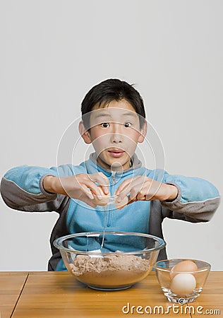 Young boy cracking egg into bowl Stock Photo