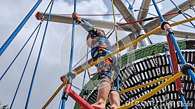 Young boy exploring a climbing frame rope ladder Stock Photo