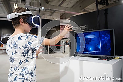 Young boy exploring computer simulation using virtual reality glasses Editorial Stock Photo