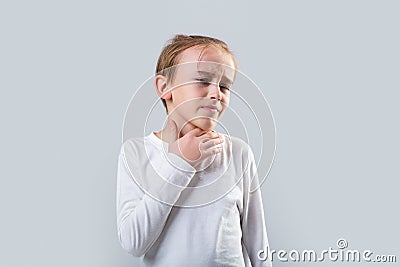 Young boy feels that his throat is pain. Ill little boy with sore throat. Ill child with sore throat. Sore throats in a Stock Photo