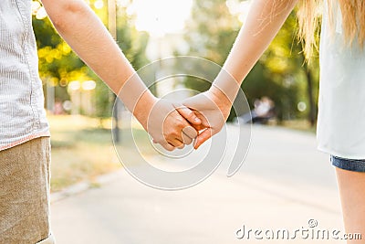 Young boy and girl hold hands and stroll in the park in sunny we Stock Photo