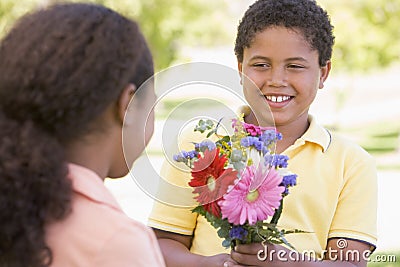 Young boy giving young girl flowers Stock Photo