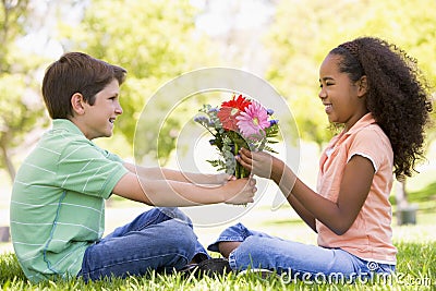 Young boy giving young girl flowers and smiling Stock Photo