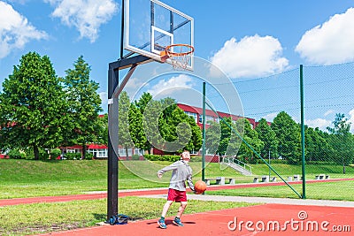 Young boy having fun playing basketball outdoors.nice,cool caucasian alone player playing basketball outdoors Stock Photo