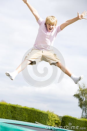 Young boy jumping on trampoline smiling Stock Photo