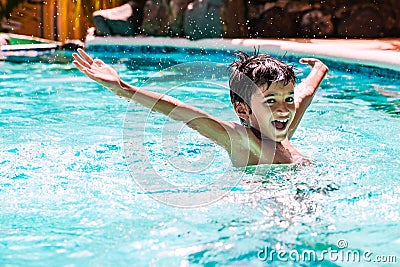 Young boy kid child eight years old splashing in swimming pool having fun leisure activity open arms Stock Photo