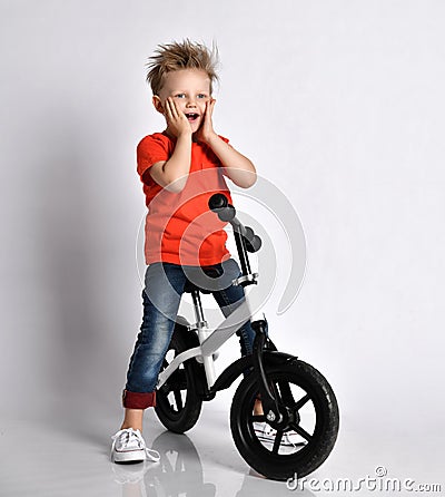 Young boy kid in orange t-shirt biker ride bicycle happy screaming Stock Photo