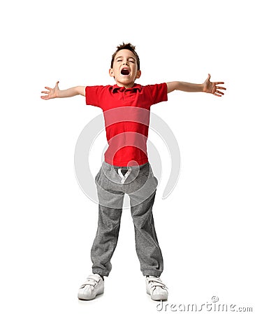 Boy kid in red t-shirt and grey pants spread hands up happy smiling screaming laughing isolated on white Stock Photo