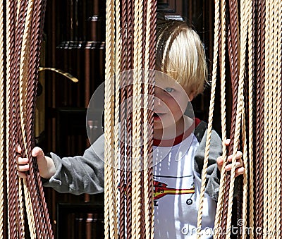 Young boy looking out from behind curtain Stock Photo