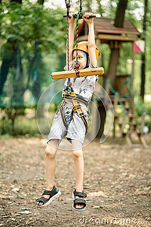 A young boy in a mountain belay and a flip flop goes through an obstacle course. Active, sporty activity in the summer for a child Stock Photo