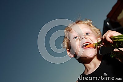 Young boy munching a carrot Stock Photo