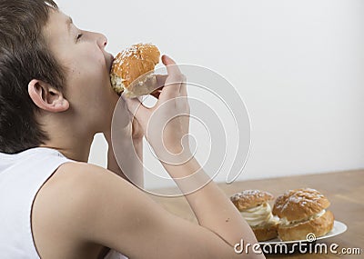 Young boy munching on a cream bun Stock Photo
